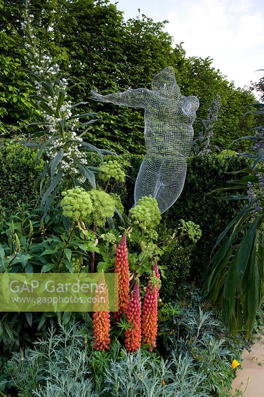 Colourful border with wire sculpture and plants including Echium pinnata and lupins