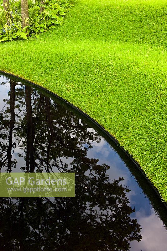 A grass amphitheatre embankment beside a pool of water in The 9 Billion Conversation Garden dat the RHS Chelsea Flower Show 2013. 