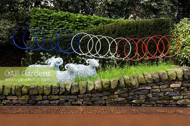 Le Jardin de Yorkshire garden with wire mesh sheep, bicycle wheel sculpture, dry stone wall and cor-ten rusted steel water trough 