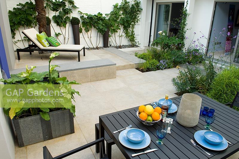 Small urban garden with dining area and lounger in background