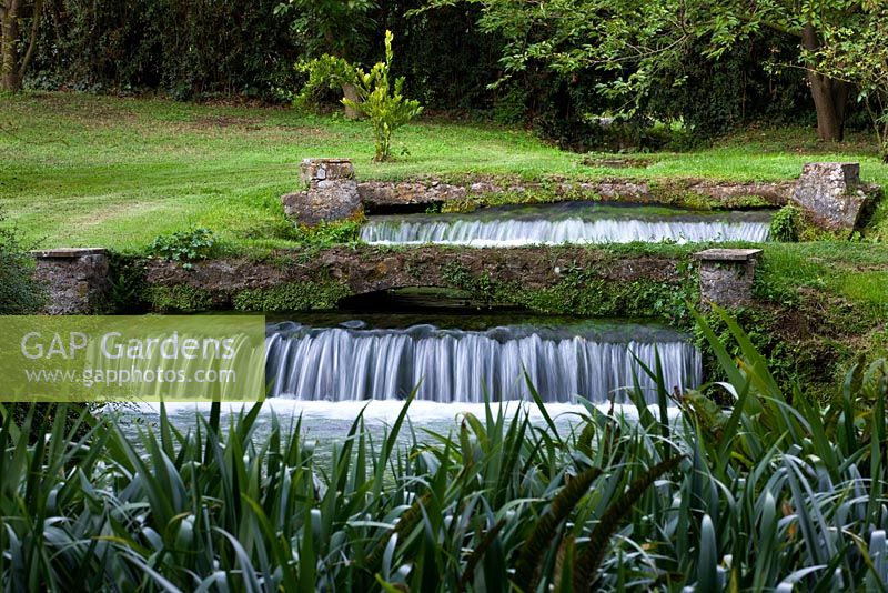 Ninfa garden, Giardini di Ninfa, Italy. Water fall in stream