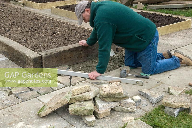 Man creating crazy paving to infill an area around raised beds