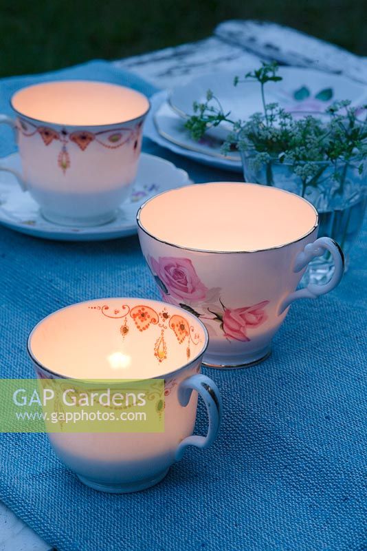 Vintage teacups used as tealight holders on a garden table