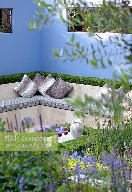 Lounge area with planting including clipped box, nepeta, Allium sphaerocephalon and Salvia 'Caradonna'. 'Layers and Links', RHS Hampton Court Flower Show 2013. Silver Gilt winner 

