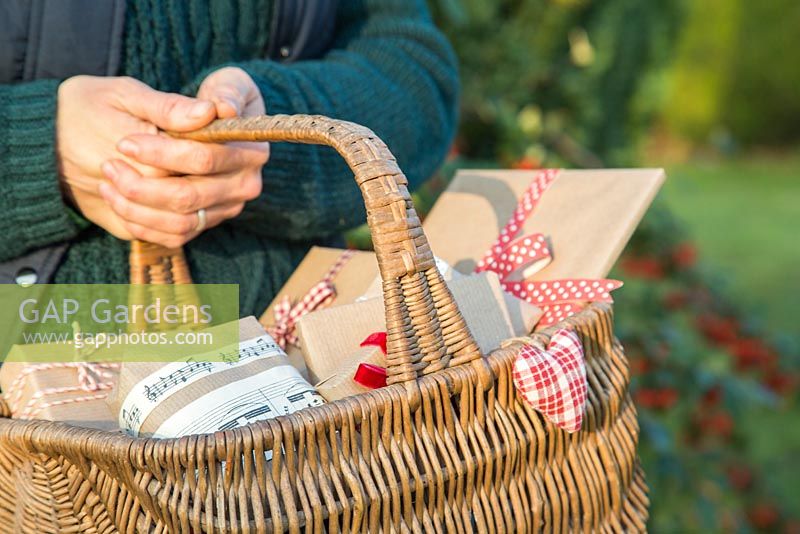 Woman carrying wicker basket full of Christmas presents