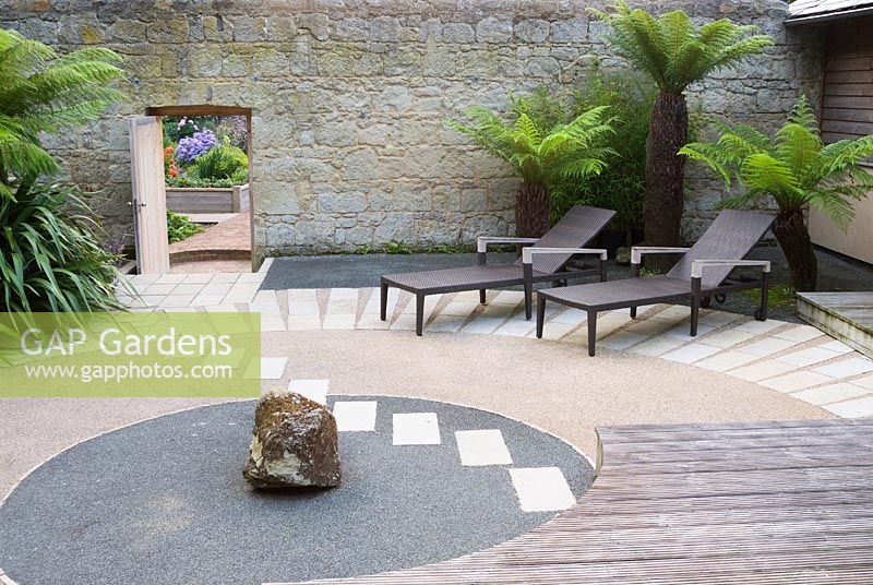 Japanese style courtyard garden beside the house features contrasting surfaces, tree ferns and outdoor furniture by Gloster.