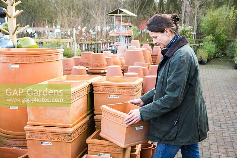 Woman browsing variety of terracotta pots  at a garden nursery
