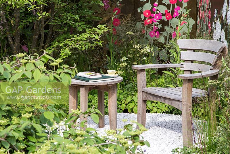 Seating area with a Leather applique backdrop displaying Magnolias, Foxgloves and Iris. Deschampsia cespitosa, Cornus kousa var. chinensis. Fresh Garden: The Massachusetts Garden. Designer: 