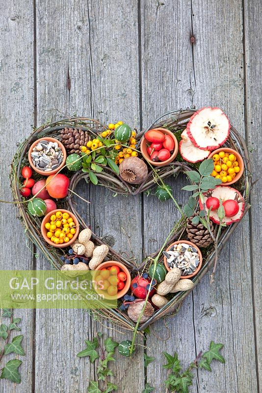 Willow heart shaped bird food display with Papaver, Malus, Pyracantha 'Soleil d'Or' and Sorbus