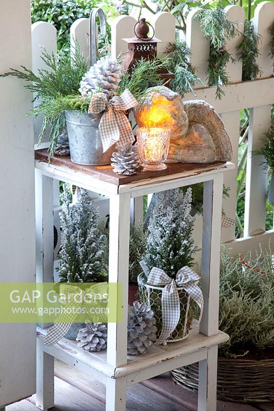 Shelving on Winter terrace with candles, pot plants and pine cone decorations
