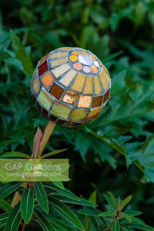 Mosaic ball on stick in the border by Anne Cardwell in town garden