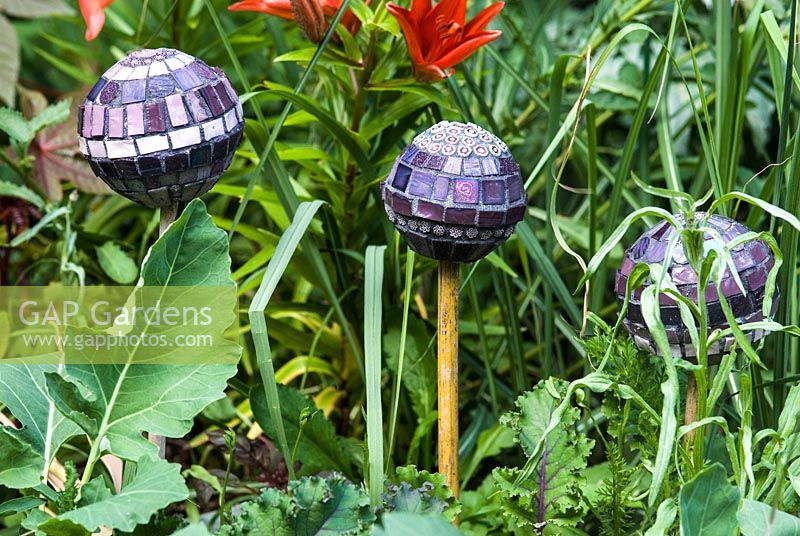 Mosaic balls on sticks, designed by Anne Cardwell, in the border with Lilies in Helen Riches town garden, June