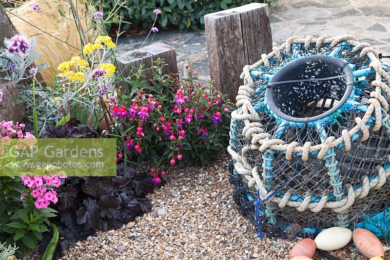 Seaside themed front garden with Lobster pot driftwood and planting includes Phlox, Fuschia, Heuchera and Verbena 
