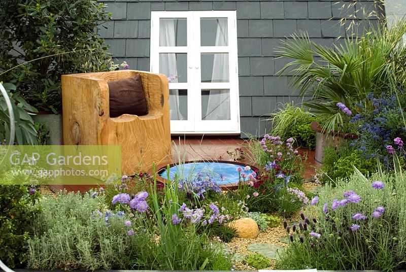 Town roof garden with hand-carved wooden seat on deck area, small pool, container planting and shingle beds