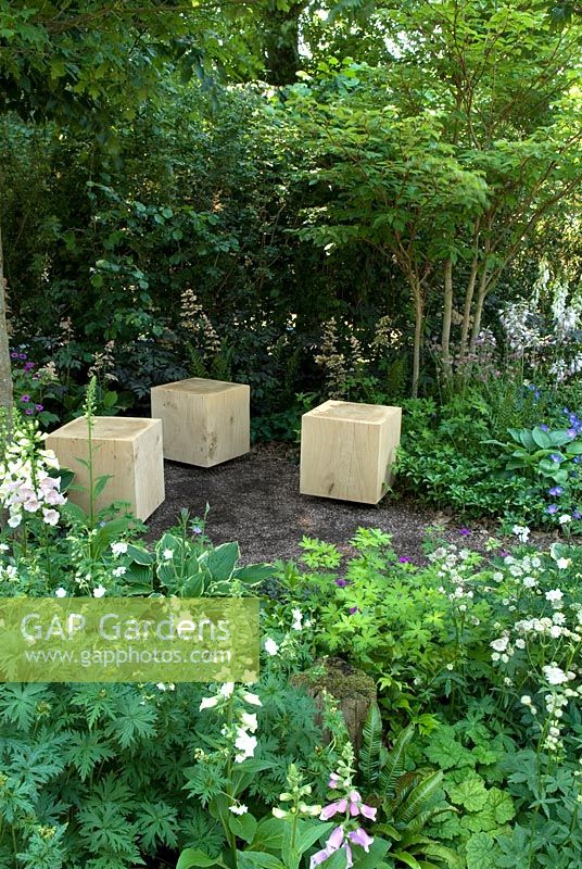 Seating within a serene woodland garden, surrounded by perennial planting to provide tranquility for enjoyment of the beauty of nature - Athanasia Summer Garden, Hampton Court Flower Show 2013