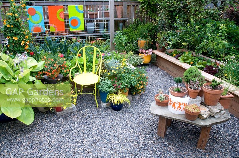 Raised bed with variety of potted plants and seating area.