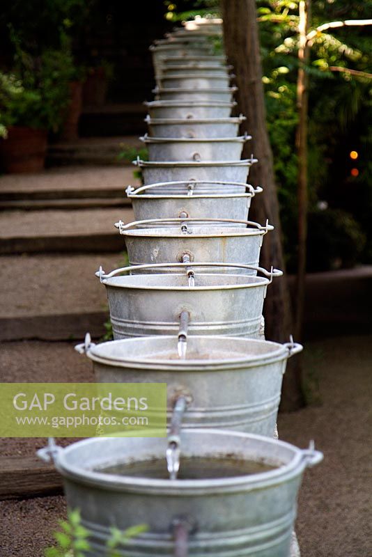 Water display consisting of a series of galvanised buckets running alongside a set of steps. Jardins des Paradis, Cordes-sur-Ciel, Tarn, France, designed to encourage children's interest in gardening. 