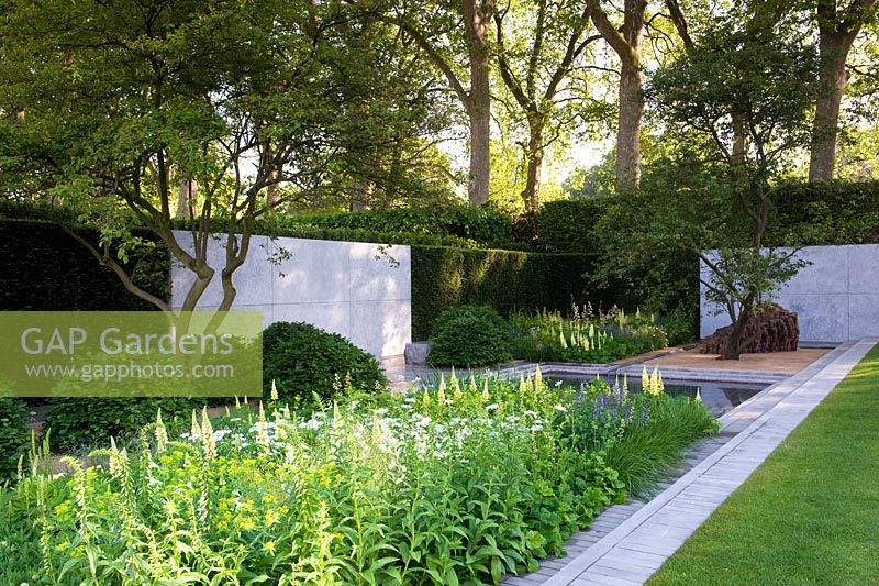 The Laurent-Perrier Garden with central square pool with water rill channels. Blocks of planting include Lupin 'Cashmere Cream' and domed beech Fagus. wooden layered cedar sculpure by Ursula von Rydingsvard Best Show Garden Gold medal 