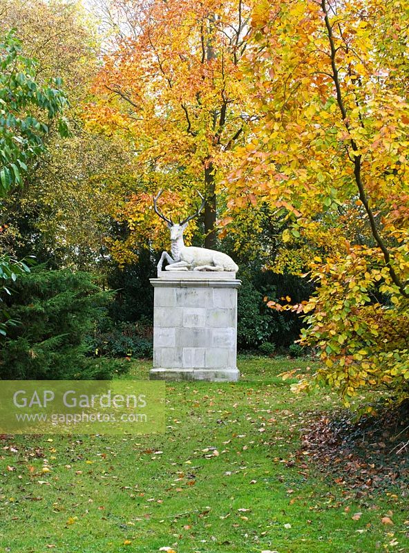 A stone stag sculpture at the east end of cross walk surrounded by autumn colour. Saling Hall, Essex
