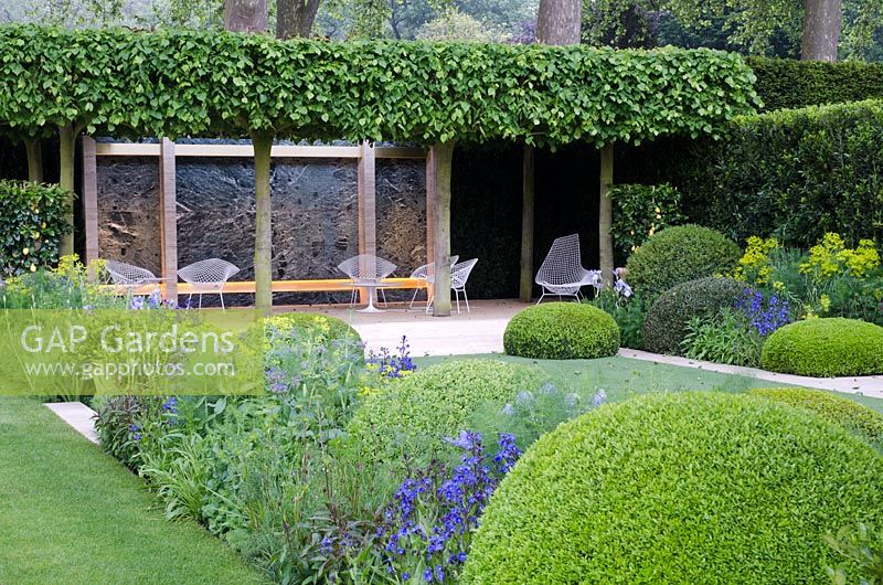 The Telegraph Garden, RHS Chelsea Flower Show 2014, gold medal winner. Borders with corners of clipped box mounds with white metal lattice seats