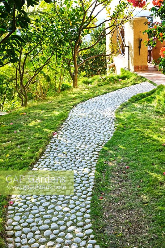 Cobbled path through lawn leading to house. Designer: Jean-Laurent Felizia, France
