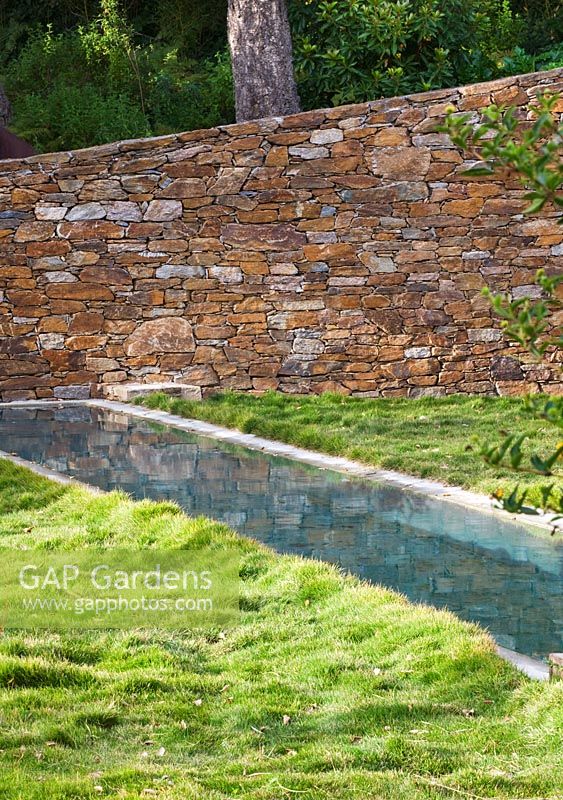 Lawn with swimming pool and rock wall. Designer: Jean-Laurent Felizia, France