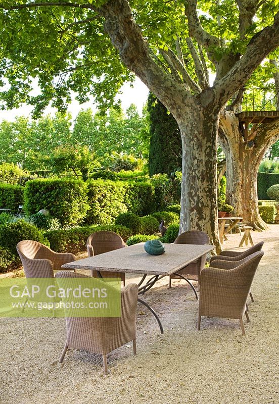 The gravel terrace beside the house with plane trees and a table and chairs - a place to sit. Les Confines, Provence, France