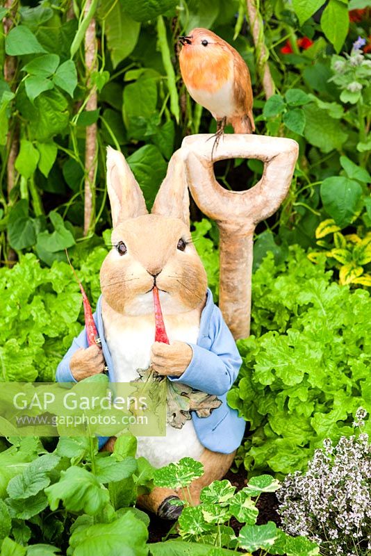 The Enchanting World of Peter Rabbit Herb Garden in the Grand Pavillion: Peter rabbit and robin on spade handle in the herb garden. 2014 RHS Chelsea Flower Show