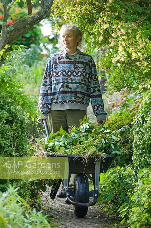 Ros Bissell with wheelbarrow. Moors meadow garden and nursery, Herefordshire