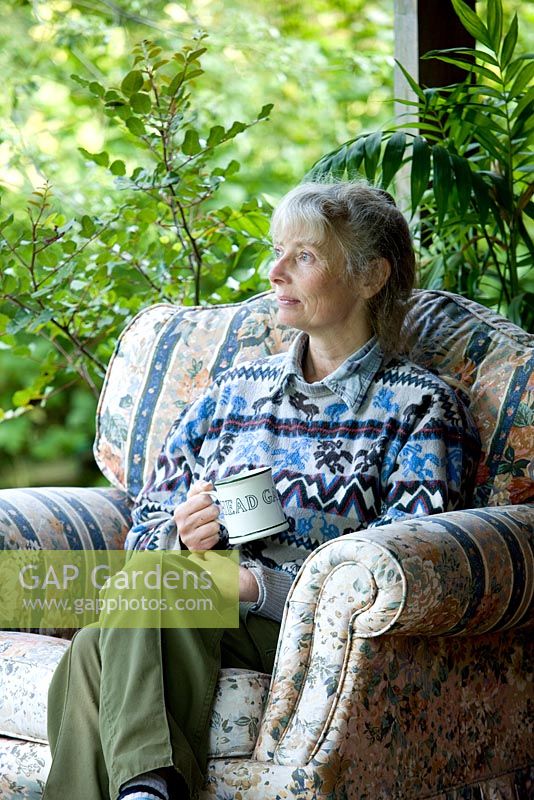 Garden and nursery owner sitting on veranda with a drink 