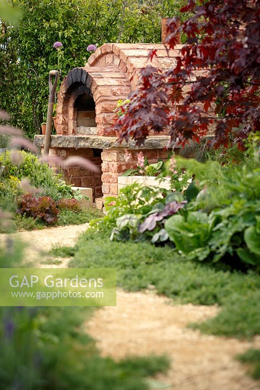Path leading to sunken area with brick pizza oven, 'A Fruity Story', show garden, RHS Malvern Spring Festival 2014