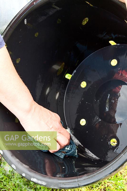 Washing a large plant pot to remove traces of soil which may harbour pests and diseases