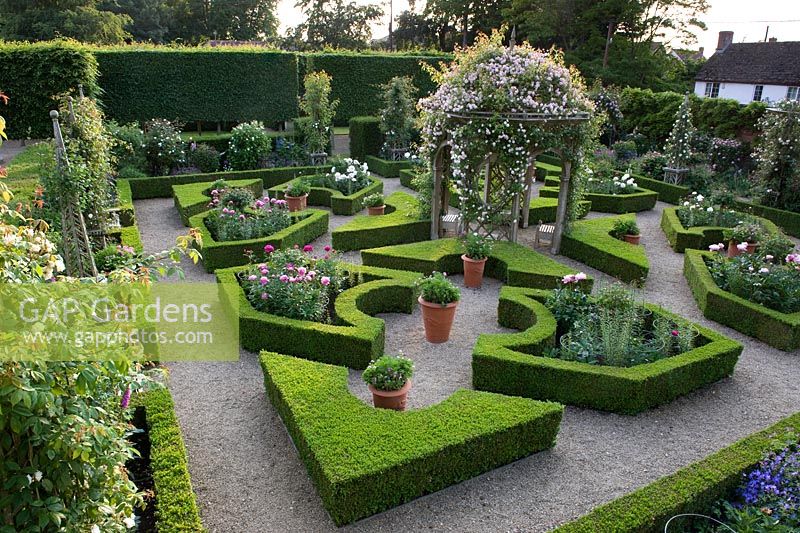  Aerial view of parterre garden with romantic English traditional style with layout of box hedging infilled with peonies and a central arbour covered with climbing rose - Seend, Wiltshire