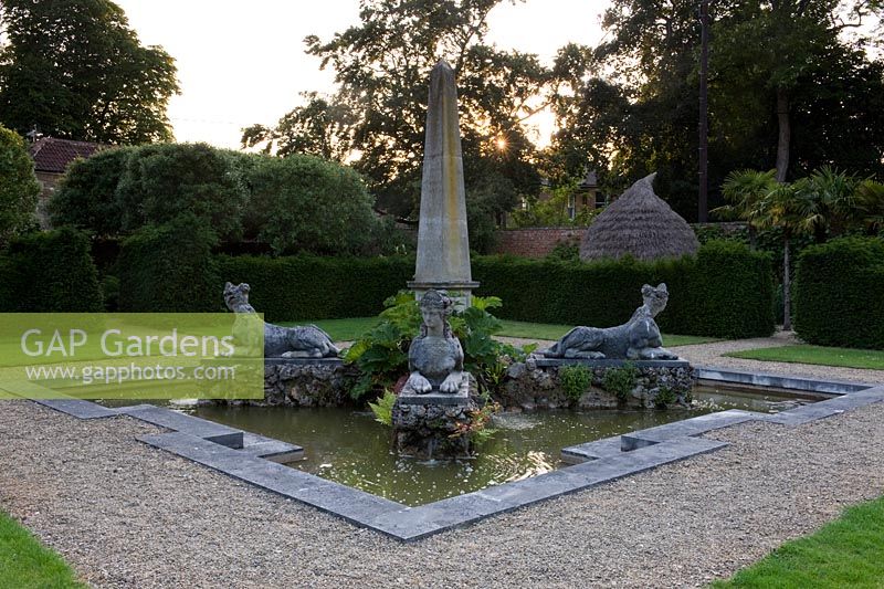 Stone obelisk with symmetrical mythical creatures at each corner set in grand ornamental pond representing Africa. Seend, Wiltshire