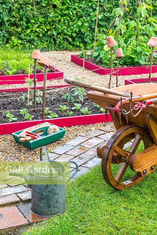 Raised beds with traditional wooden wheelbarrow and garden tools