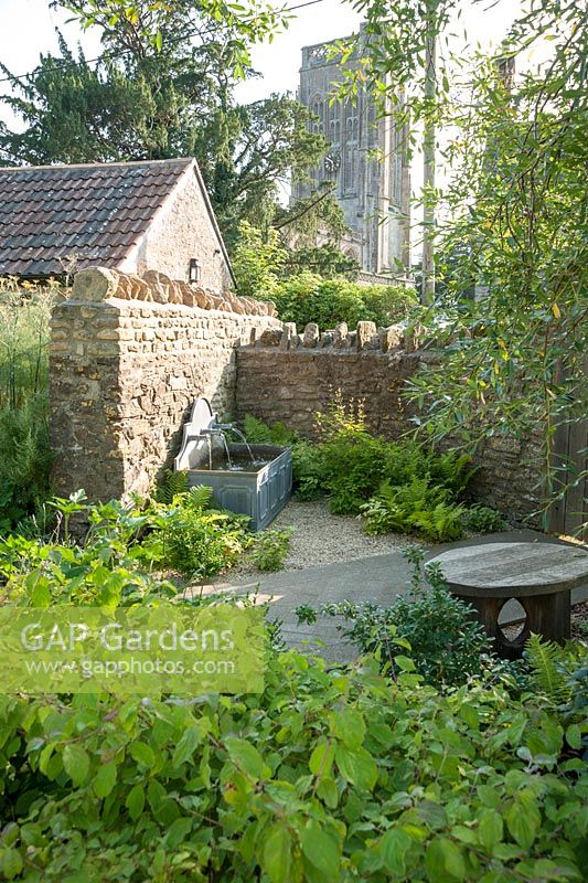 Water feature with tower of the Church of St Mary beyond. Old Rectory, Batcombe, Somerset, UK