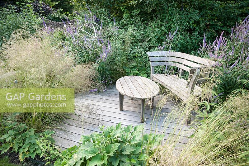 Decked seating area with bench and table surrounded by Veronicastrum virginicum 'Fascination'. Old Rectory, Batcombe, Somerset, UK