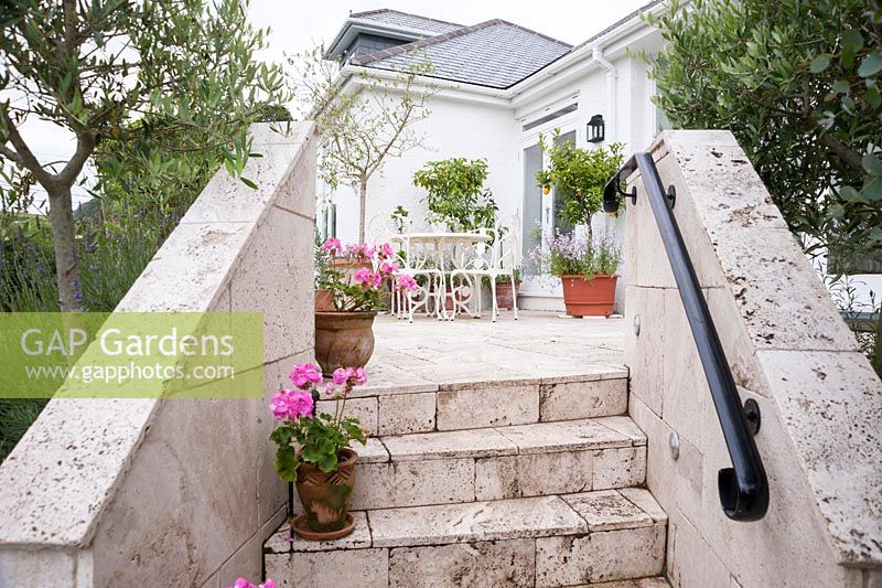 Steps and terrace are made of white travertine, with pots of pink pelargoniums and citrus trees adding to a Mediterranean feel. Parc-Lamp, Ruan Lanihorne, Truro, Cornwall, UK
