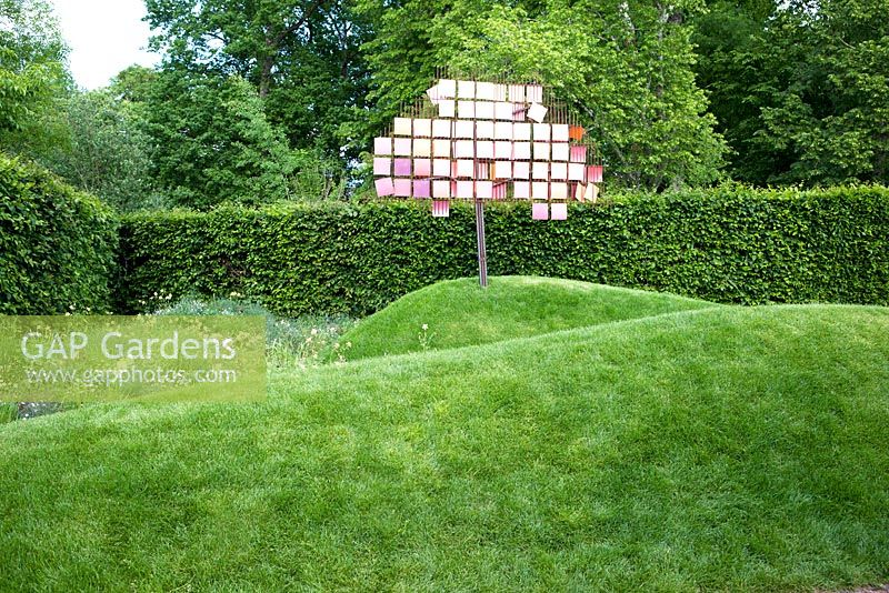 Title: Les Couleurs du Peche. Modern garden with sculpture on small hill