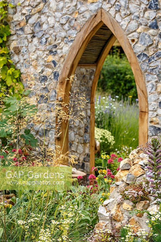 Flint priory ruin feature with grasses and naturalistic planting, The Flintknapper's Garden - A Story of Thetford, RHS Hampton Court Flower Show 2014