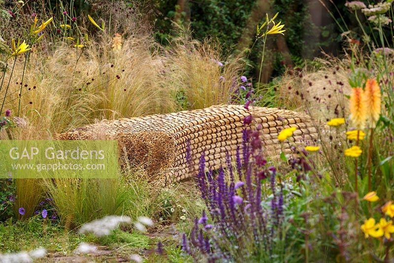 Sculptured straw bench amongst naturalistic grasses and perennials, The Jordans Wildlife Garden, RHS Hampton Court Flower Show 2014
