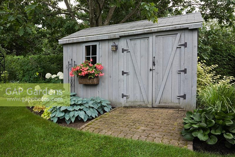 GAP Gardens - Old grey wooden storage shed bordered by 