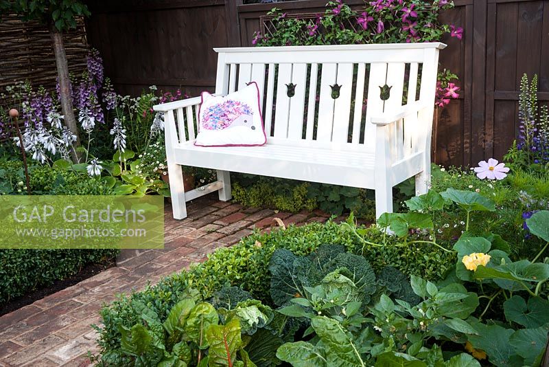 Hedgehog Garden - view of garden bench, brick paving and box hedge with savoy cabbage, chard and squash - Designer - Tracy Foster - Sponsor - Peoples Trust for Endangered Species PTES - British Hedgehog Preservation Society BHPS