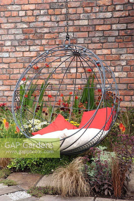 ndustrial Transitions - swing seat in outdoor living area planting of Crocosmia 'Lucifer' Helenium and red hot pokers 