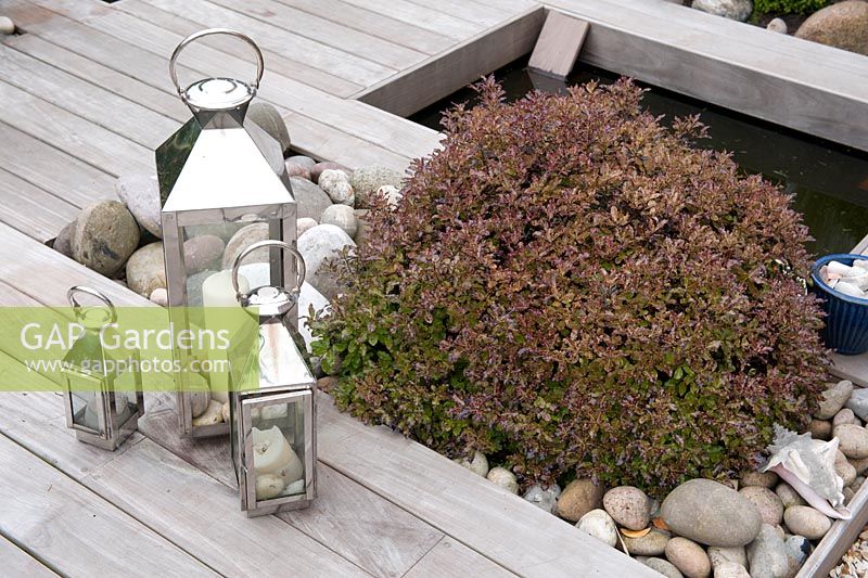 Lpe hardwood contemporary deck with contrasting texture of rounded pebbles, stainless steel candle holders