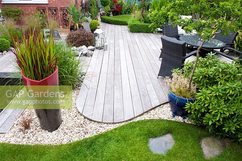 Curved sinuous edge of Ipe hard wood deck contrasts with curve of lawn with crisp metal edging and 20 ml gravel