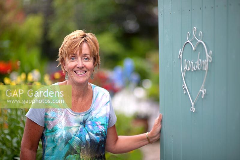 Angie Barker, garden designer at the gate of her own garden