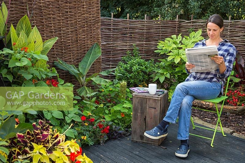 Woman reading a newspaper, relaxing in her garden retreat