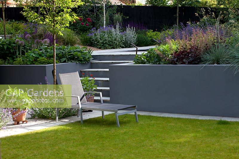 Sun lounger next to grey retaining walls, lounger, Flowerbeds and container planting 