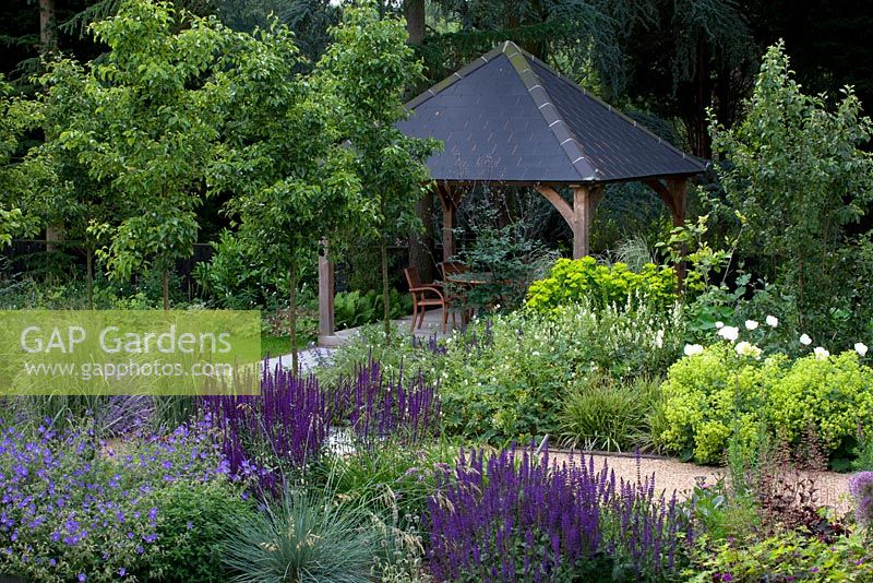 View to covered dining area, mixed flowerbeds and trees -  Pyrus 'Chanticleer'
